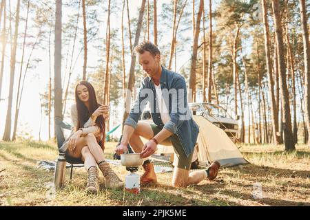Preparazione del cibo. Una giovane coppia viaggia insieme nella foresta di giorno Foto Stock