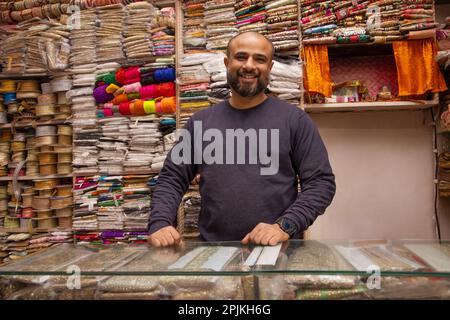 Ritratto di un allegro custode del negozio in piedi presso la sua negozio di merletti Foto Stock