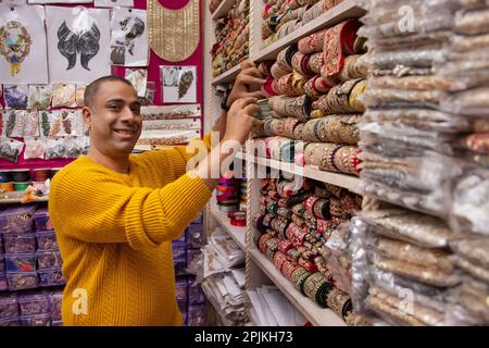 Ritratto di un allegro custode del negozio in piedi presso la sua negozio di merletti Foto Stock