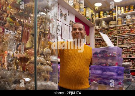 Ritratto di un allegro custode del negozio in piedi presso la sua negozio di merletti Foto Stock