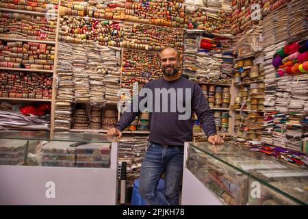 Ritratto di un allegro custode del negozio in piedi presso la sua negozio di merletti Foto Stock