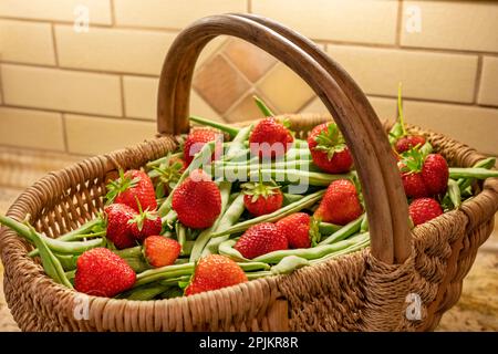 Issaquah, Stato di Washington, Stati Uniti. Cesto di fagioli verdi appena raccolti e fragole seduto su un piano di granito cucina. Foto Stock