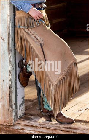 USA, Shell, Wyoming. Hideout Ranch cowgirl in piedi nella porta con stivali da cowboy e cappe (PR,MR) Foto Stock