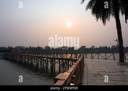 Ponte di legno sul lago. Impostazione SEN in background. Foto Stock