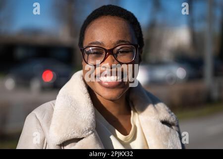 Primo piano all'aperto ritratto di felice afro-americana donna in giornata di sole. Foto Stock
