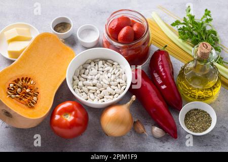 Ingredienti per minestrone di verdure: Zucca, fagioli bianchi, pomodori, peperoni, cipolle, aglio, sedano, pasta, erbe, formaggio, olio d'oliva, spic Foto Stock