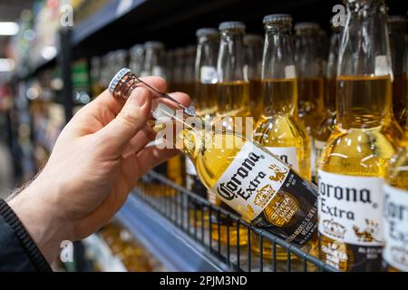 L'acquirente prende la birra Corona Extra nel supermercato. La mano tiene la birra Corona Extra. Minsk, Bielorussia, 2023 Foto Stock