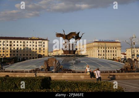 Una coppia scatta una foto vicino alla statua della cicogna sulla cupola in Piazza dell'Indipendenza (ex Piazza Lenin) a Minsk, Bielorussia; l'ufficio postale principale sullo sfondo Foto Stock