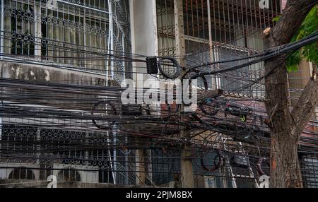 Elettricità disordinata e fili internet sul palo, caos di cavi e fili su un palo di elettricità in Thailandia Foto Stock