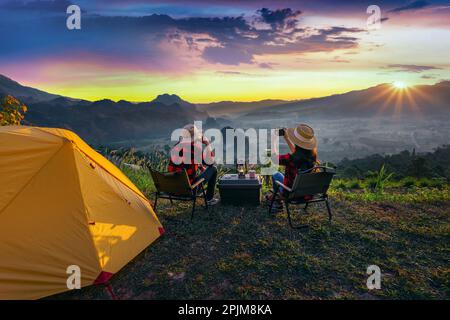 Coppia romantica campeggio all'aperto e scattare foto con la macchina fotografica mentre campeggio all'alba. Phu Lang Ka, provincia di Pha yao in Thailandia. Foto Stock