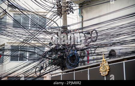 Elettricità disordinata e fili internet sul palo, caos di cavi e fili su un palo di elettricità in Thailandia Foto Stock