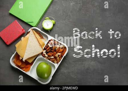 Composizione piatta con pranzo e cibo appetitoso per la scuola su sfondo grigio Foto Stock