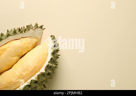Pezzi di durian fresco maturo su fondo beige, piatto. Spazio per il testo Foto Stock