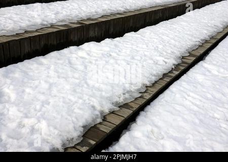 Fusione sulla neve primaverile sulle diverse superfici di vecchie tavole di legno marrone superficie esterna vista laterale primo piano Foto Stock