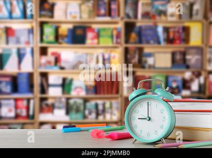 Turchese sveglia e diverse cancelleria su tavolo in legno in biblioteca, spazio per il testo Foto Stock