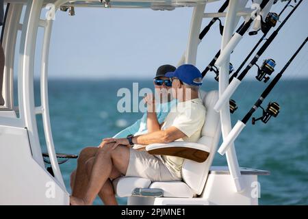 Due uomini seduti su una barca da pesca con console centrale. Foto Stock