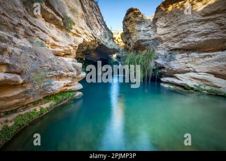 Bellissimo ambiente di una cascata chiamata Salto del Utro a Bullas, Murcia, Spagna. Acque blu e cristalline sotto una grotta di roccia gialla Foto Stock