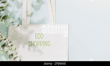 Concetto di shopping, acquisto o vendita sostenibile. Eco friendly vita morta con borsa in tessuto bianco con testo Eco shopping su sfondo blu con Foto Stock