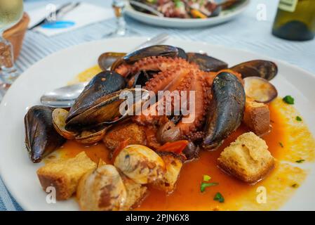 Stufato in salsa di pomodoro Octopus con frutti di mare e crostini. Foto Stock