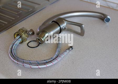 Un nuovo rubinetto da cucina è dotato di tubi flessibili per l'installazione sul lavello Foto Stock