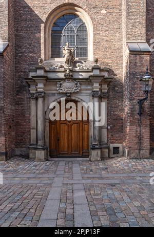 Copenaghen, Danimarca - 13 settembre 2010: Sankt Petri Kirke, St.. Entrata della Chiesa di Peters, porta in legno marrone, colonne scolpite come cornice con statua di Foto Stock