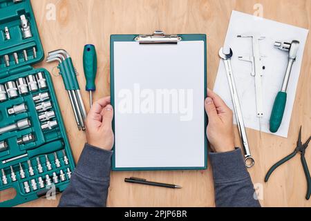 Uomo che lavora in officina tenendo gli appunti utilizzando molti strumenti. Chiave, chiave, pinza e cricchetto con molti accessori. Attrezzature. Utensile universale se Foto Stock