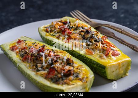 Zucchine farcite con gamberetti, verdure e formaggio. Zuccini al forno, primo piano Foto Stock