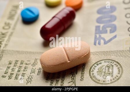 Primo piano delle pillole mediche con banconote in valuta indiana Foto Stock