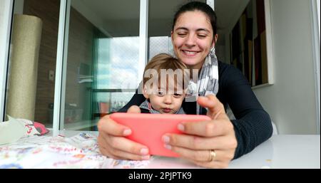 Genitori e figli che usano il cellulare. Madre e bambino che tengono lo smartphone Foto Stock