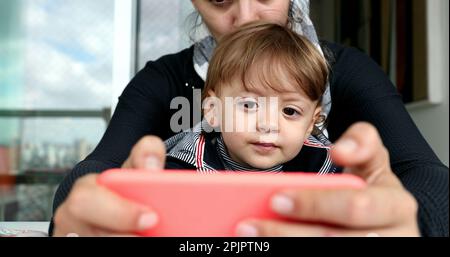 Genitori e figli che usano il cellulare. Madre e bambino che tengono lo smartphone Foto Stock