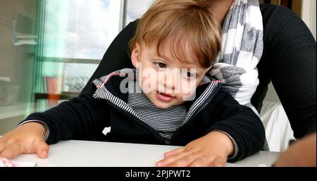 Bambino in giro per la madre, genitore che tiene il cellulare multi-tasking Foto Stock