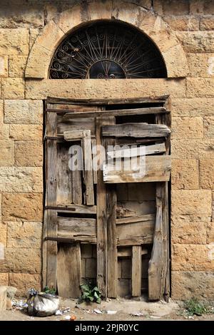 Una porta di legno chiusa con molte lastre con un arco sopra, tipici dettagli architettonici libanesi. Foto Stock
