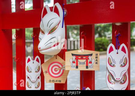 Mascherine di volpe rosse e bianche e placche di preghiera ema ad Asanogawa inari jinja, Kanazawa, Giappone. TRADUZIONE. a sinistra: preghiera per il successo scolastico. diritto: adempiere Foto Stock