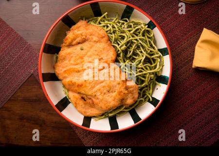 Pasta verde con pollo fritto cibo peruviano tavola a buffet assortiti piatti gourmet cucina Perù tradizionale Foto Stock