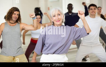 Giovane donna allegra imparando una nuova danza moderna nella lezione di danza di gruppo Foto Stock