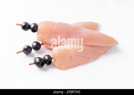 Pollo crudo interno su spiedini con olive su fondo bianco. Carne di pollo crudo crudo, kebab su spiedini su fondo bianco. Spiedini di carne cruda Foto Stock