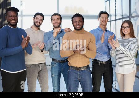 Ritratto di giovani overjoyed lavoratori diversificati che battono le mani Foto Stock
