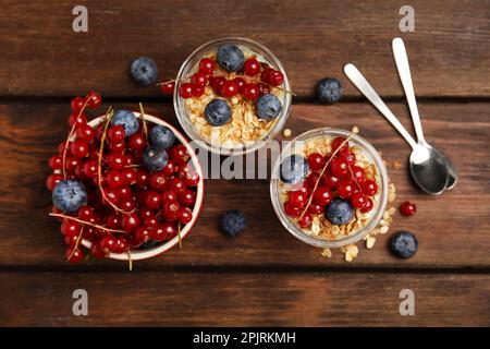 Delizioso parfait di yogurt con frutti di bosco freschi su tavolo di legno, piatto Foto Stock