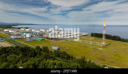 Terminale per gas e petrolio con combustione a fiamma di gas di scarico combustibili durante la produzione di petrolio. Serbatoi di stoccaggio dell'olio a terra nella stazione di distribuzione dell'olio. Borneo, Sabah, Malesia. Foto Stock