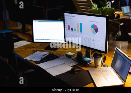 Primo piano della scrivania con computer portatili, computer, documenti e notebook, lavorando fino a tardi in ufficio Foto Stock