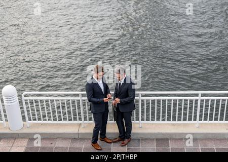 Allegro uomo d'affari medio-orientale a piedi per strada verso un moderno edificio di uffici. Ritratto di persone di successo business all'aperto, parlando insieme Foto Stock