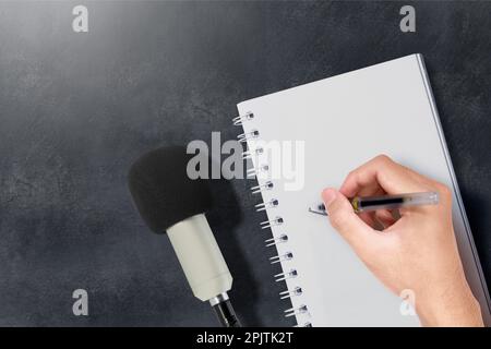 Microfoni e umani scrivono qualcosa sulla carta. Concetto di giornata mondiale della libertà di stampa Foto Stock