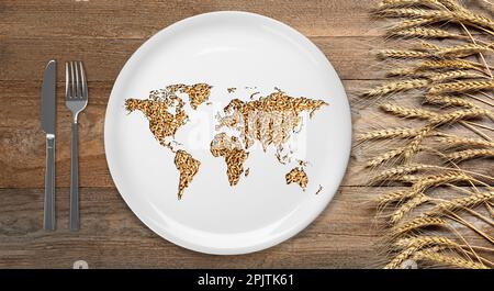 Concetto di crisi alimentare globale. Mappa del mondo fatta di grani di grano in piatto, posate e punte su tavola di legno, piatto Foto Stock