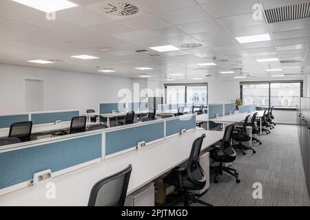 Ufficio vuoto in tonalità di grigio con lunghi tavoli e sedie per dipendenti di manager con ampie finestre con luce naturale. Concetto di ufficio per Foto Stock