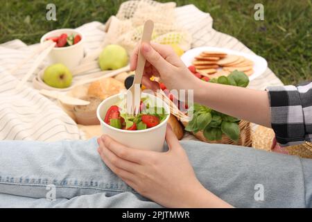 Ragazza che ha pic-nic su erba verde nel parco, primo piano Foto Stock