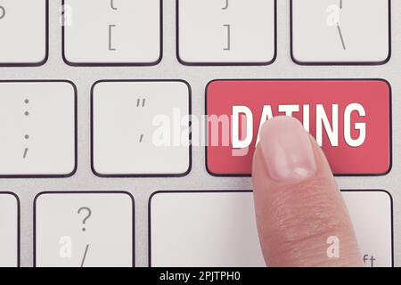 Vista dall'alto della donna che preme il tasto con la parola datazione sulla tastiera del computer, primo piano Foto Stock