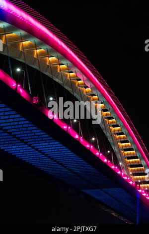 Questa splendida immagine è caratterizzata da un vivace ponte illuminato nel cielo notturno, illuminato da una serie di colori vivaci Foto Stock