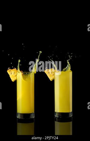 succo di ananas in un bicchiere su sfondo nero con riflessi e schizzi. Foto di alta qualità Foto Stock