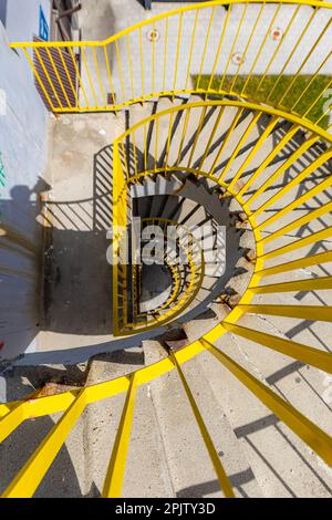 Rzeszow, Polonia - Giugno 2022: Vista dall'alto di una scala a chiocciola in cemento con ringhiere gialle in una mattinata soleggiata Foto Stock