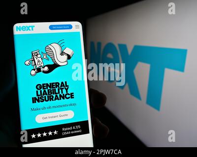 Persona in possesso di smartphone con pagina Web della società finanziaria statunitense Next Insurance Inc. Sullo schermo di fronte al logo. Messa a fuoco al centro del display del telefono. Foto Stock